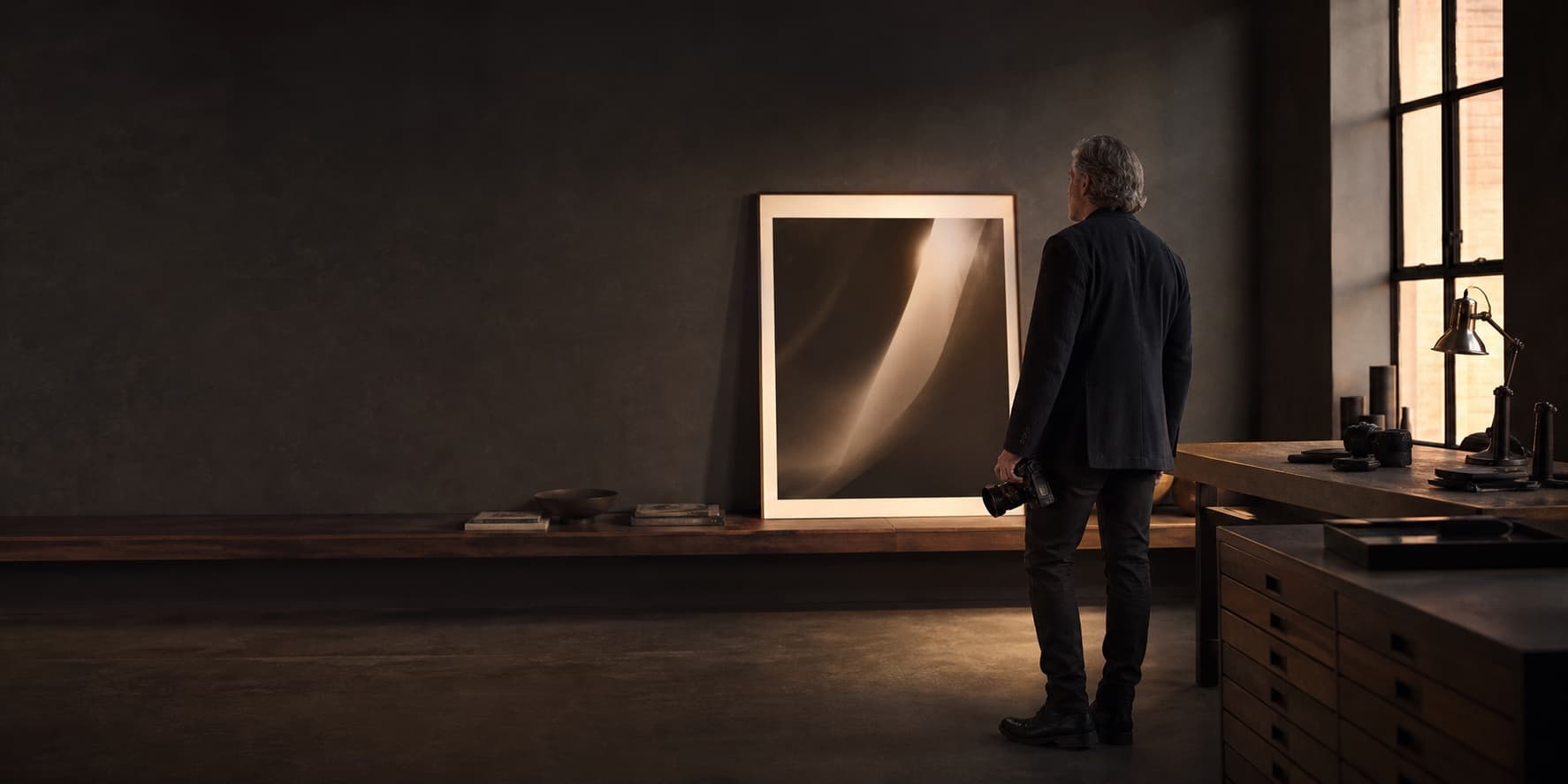 A photographer considering a finished print in a warm, quiet studio